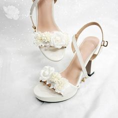 a pair of white high heel shoes with flowers on the side and straps around the ankles