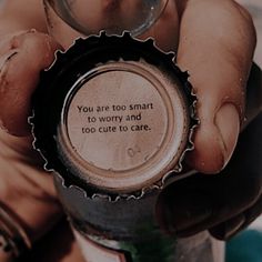 a person holding a bottle cap that says you are too smart to worry and too cute to care