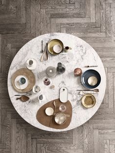 a white table topped with lots of dishes on top of a wooden floor covered in plates and cups