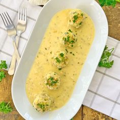 a white plate topped with meatballs covered in gravy and garnished with parsley