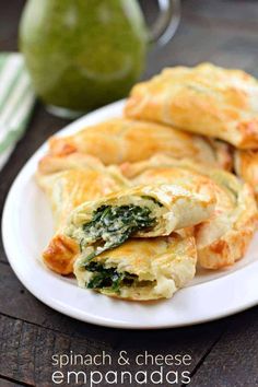 spinach and cheese empanadas on a white plate next to a green pitcher