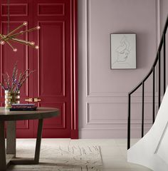 a living room with red walls and a round table in front of a staircase that leads up to the second floor