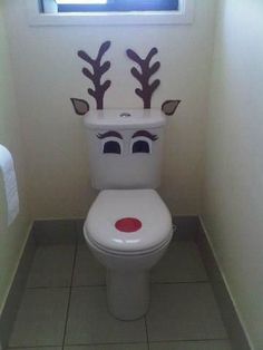 a white toilet sitting in a bathroom next to a window with reindeer decorations on it