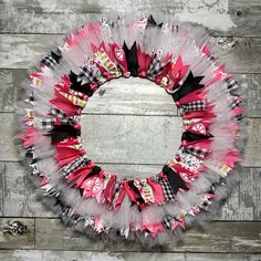 a wreath made out of tulle and bows on top of a wooden floor next to a wall