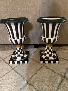 two black and white vases sitting next to each other on a carpeted floor