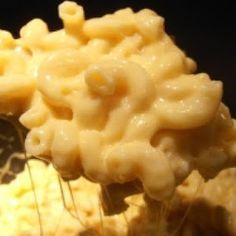 macaroni and cheese being stirred with a whisk in a black bowl