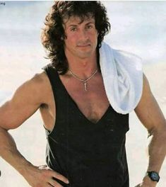 a man with his hands on his hips wearing a black tank top and white towel