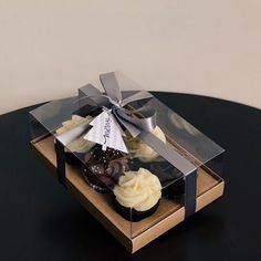 a cupcake in a clear box with a ribbon around it sitting on a table