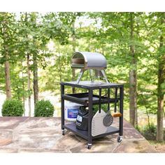 an outdoor bbq grill on top of a stone patio with trees in the background