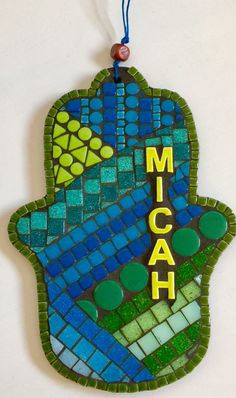 a mosaic hamsa hanging on a wall with the word mich written in yellow