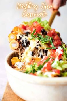 a close up of a bowl of food with a spoon in it and the words walking taco casserole