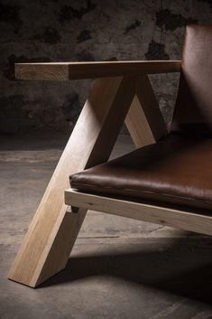 a brown leather chair sitting on top of a cement floor next to a stone wall