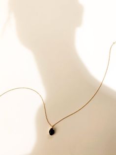 the shadow of a woman wearing a necklace with a black bead hanging from it