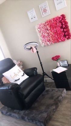 a living room with a black chair and pink flowers on the wall