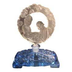 a glass figurine sitting on top of a blue base with an infant in the center