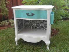 a white and blue nightstand sitting in the grass