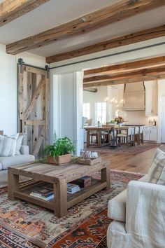 a living room filled with furniture next to a wooden table and white couches in front of a sliding barn door