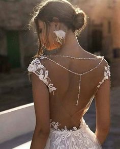 the back of a woman's wedding dress with white flowers and pearls on it