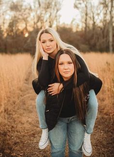 two women are hugging in the middle of a field