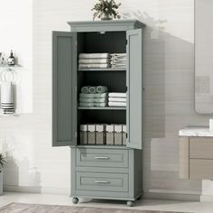 a tall cabinet with towels on top of it in a white and gray room next to a sink