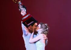 a man and woman kissing each other with a trophy on their head in front of them