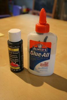 two bottles of glue sitting on top of a wooden table