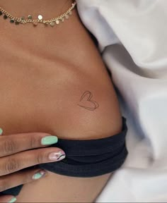 a woman's stomach with a small heart tattoo on her left side ribcage