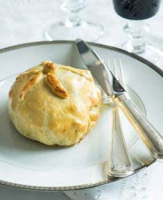 a white plate topped with a pastry on top of a table next to silverware