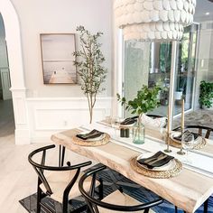 a dining room table with two chairs and a large mirror in the corner behind it