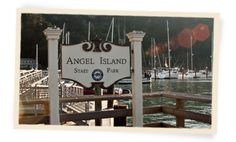 an angel island state park sign in front of the water with sailboats on it