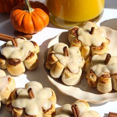 cinnamon buns with icing and pecans are on plates next to a glass of orange juice