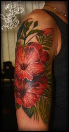 a woman's arm with red flowers and green leaves on the back of it