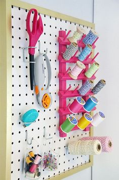 a peg board with scissors and other crafting supplies on it, hanging from the wall