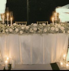 a table with candles and flowers on it at a wedding or other function in the evening