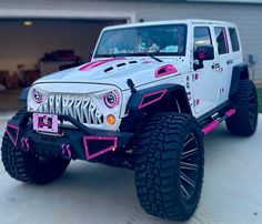 a white jeep with pink accents parked in front of a garage door on a driveway