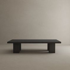 a black table sitting on top of a floor next to a white wall in an empty room