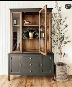 an old china cabinet is painted green and has plants in the top shelf, along with a potted olive tree