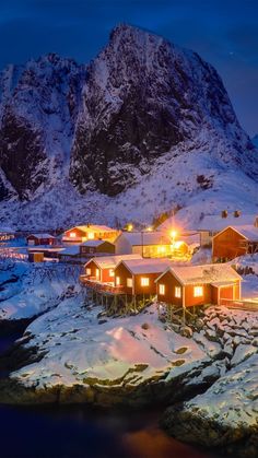 a snowy mountain with some houses and lights in the snow on it's side