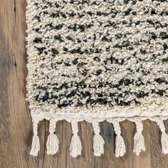 a black and white rug with tassels on it sitting on a wooden floor