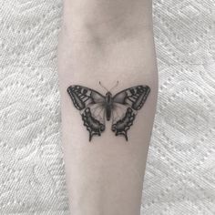 a black and white butterfly tattoo on the left calf area, with one wing spread out