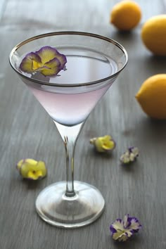 a glass filled with liquid next to lemons and flowers