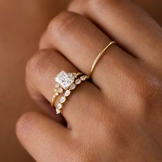 a woman's hand with a diamond and gold ring on her left hand,