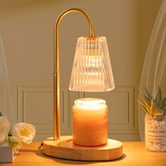 a table lamp sitting on top of a wooden table next to a vase with flowers