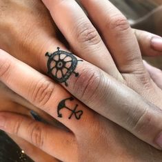 two people holding hands with tattoos on their fingers and the other hand has a wheel