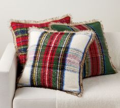 two plaid pillows sitting on top of a white couch