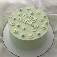 a green birthday cake with white and yellow flowers