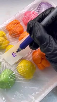 a gloved hand in black gloves holding a marker over plastic bags filled with colored candies