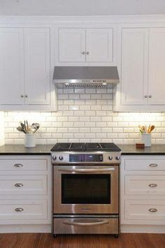 a kitchen with white cabinets and stainless steel stove top oven in front of an appliance