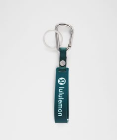 a green lanyard keychain hanging from a metal hook on a white surface