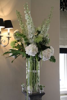 a vase filled with lots of white flowers on top of a table next to a lamp